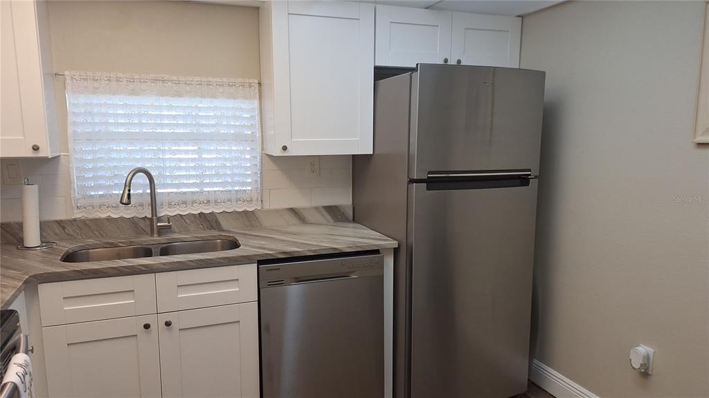A kitchen features white cabinets, stainless steel appliances, and a gray patterned countertop — 809 RUSSELL LANE UNIT 323, BRANDON, FL