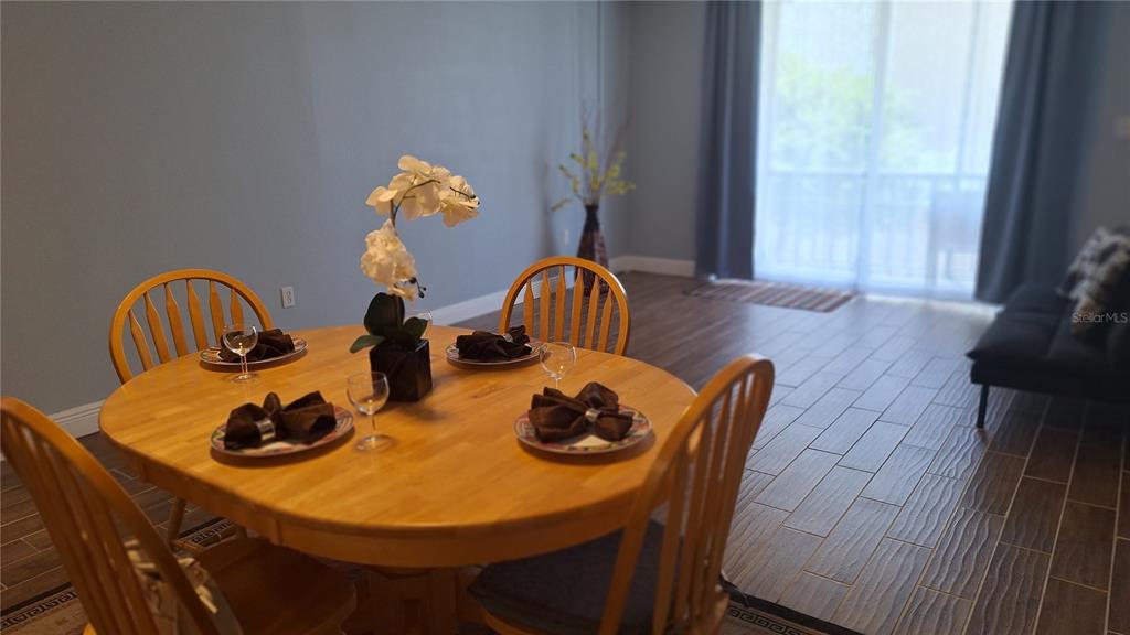 A dining area features a wooden table with four chairs and tile flooring — 809 RUSSELL LANE UNIT 323, BRANDON, FL