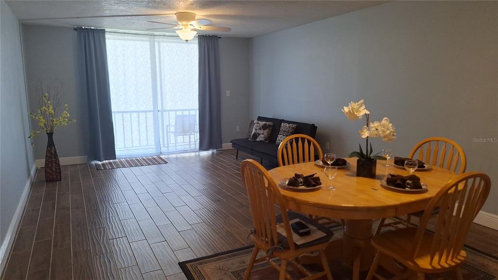 A dining area with a wooden table and chairs sits in front of a living space — 809 RUSSELL LANE UNIT 323, BRANDON, FL