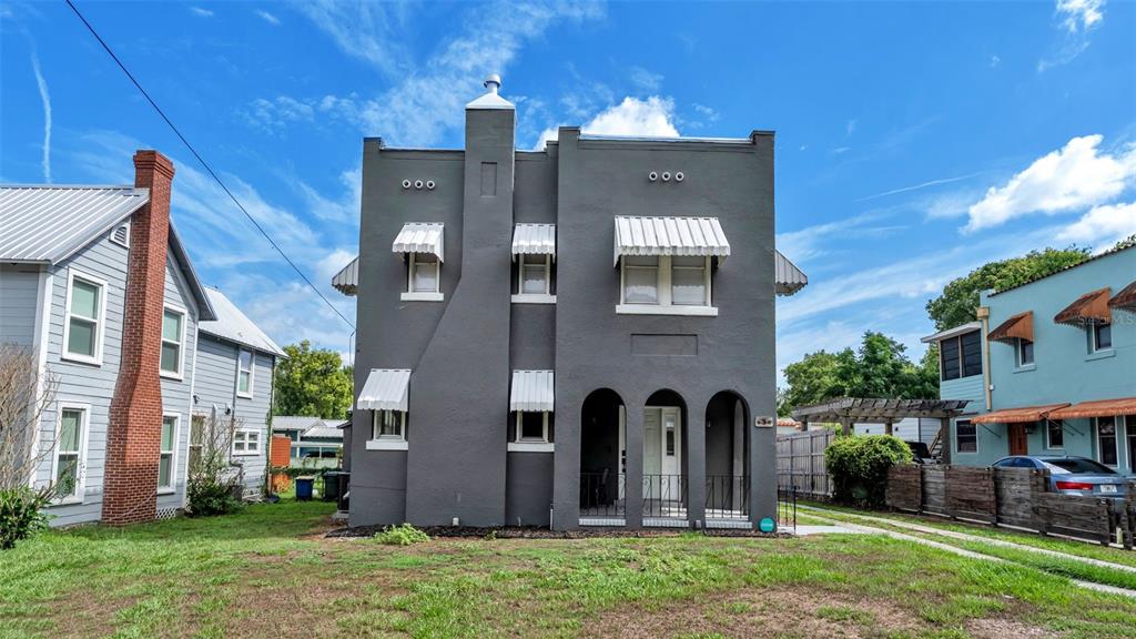 A two-story gray stucco house with arched entryways and white window awnings under a sky — 630 E STANFORD STREET, BARTOW, FL