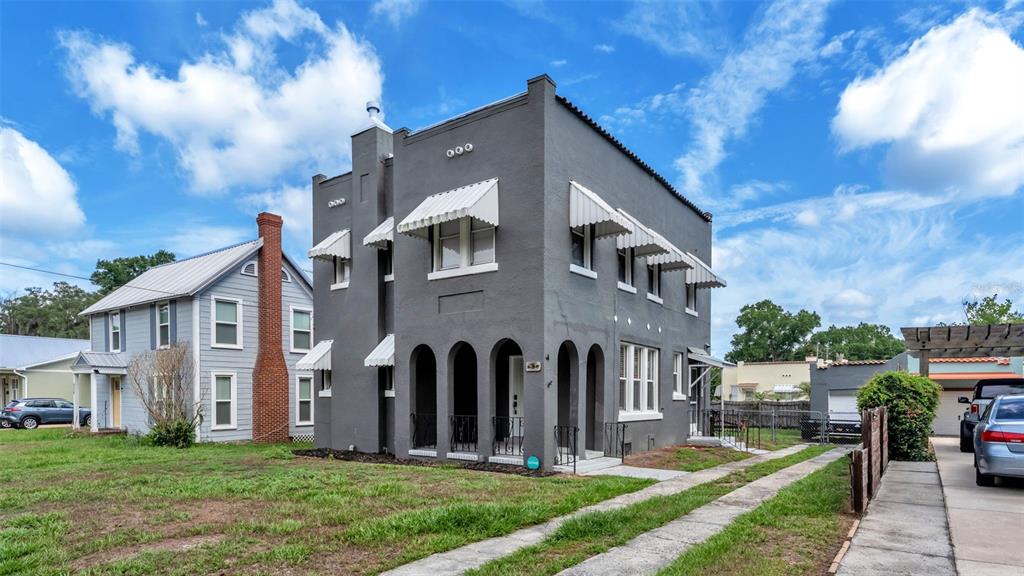 A two-story gray stucco building with arched porch openings and metal window awnings — 630 E STANFORD STREET, BARTOW, FL