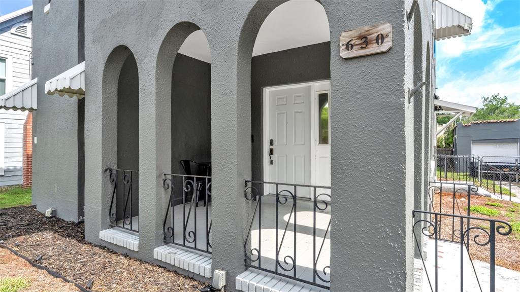 A gray stucco house exterior features three arched porch openings with black wrought iron railings — 630 E STANFORD STREET, BARTOW, FL