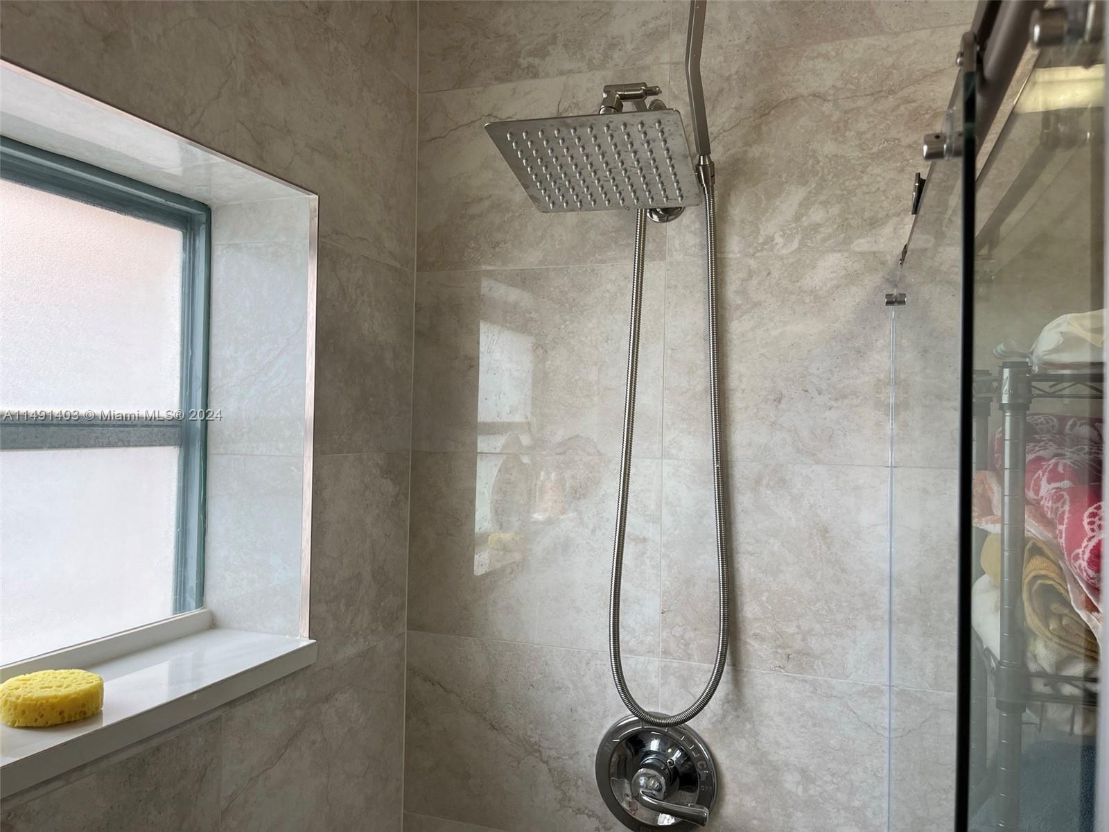 A tiled shower stall features a square rainfall showerhead and a window — 181 NE 14th Ave # 22B, Hallandale Beach FL 33009, HALLANDALE BEACH, FL