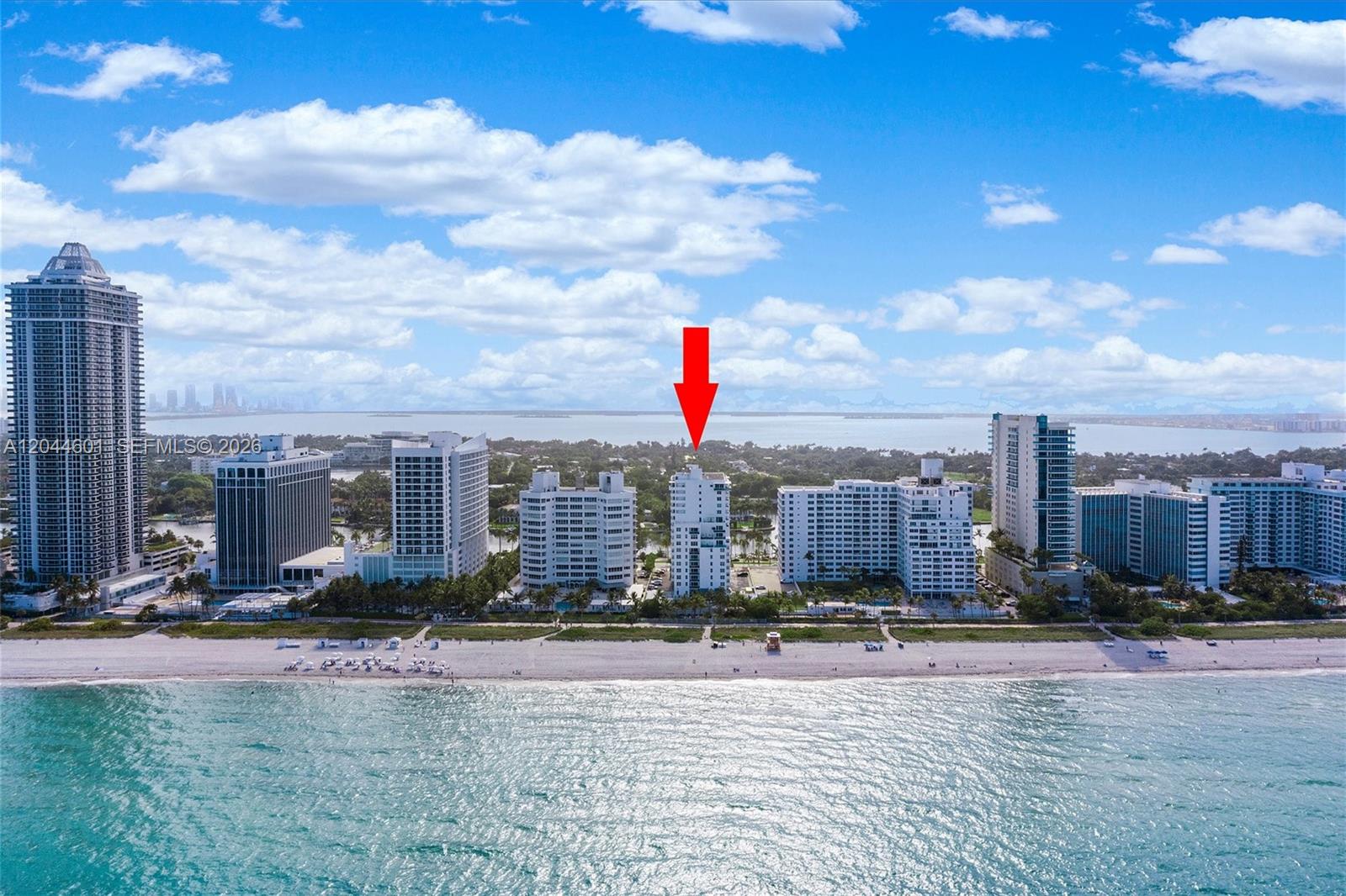 An aerial view shows a white residential building marked by a red arrow on a beach — 5001 Collins Ave # 9H, Miami Beach FL 33140, MIAMI BEACH, FL
