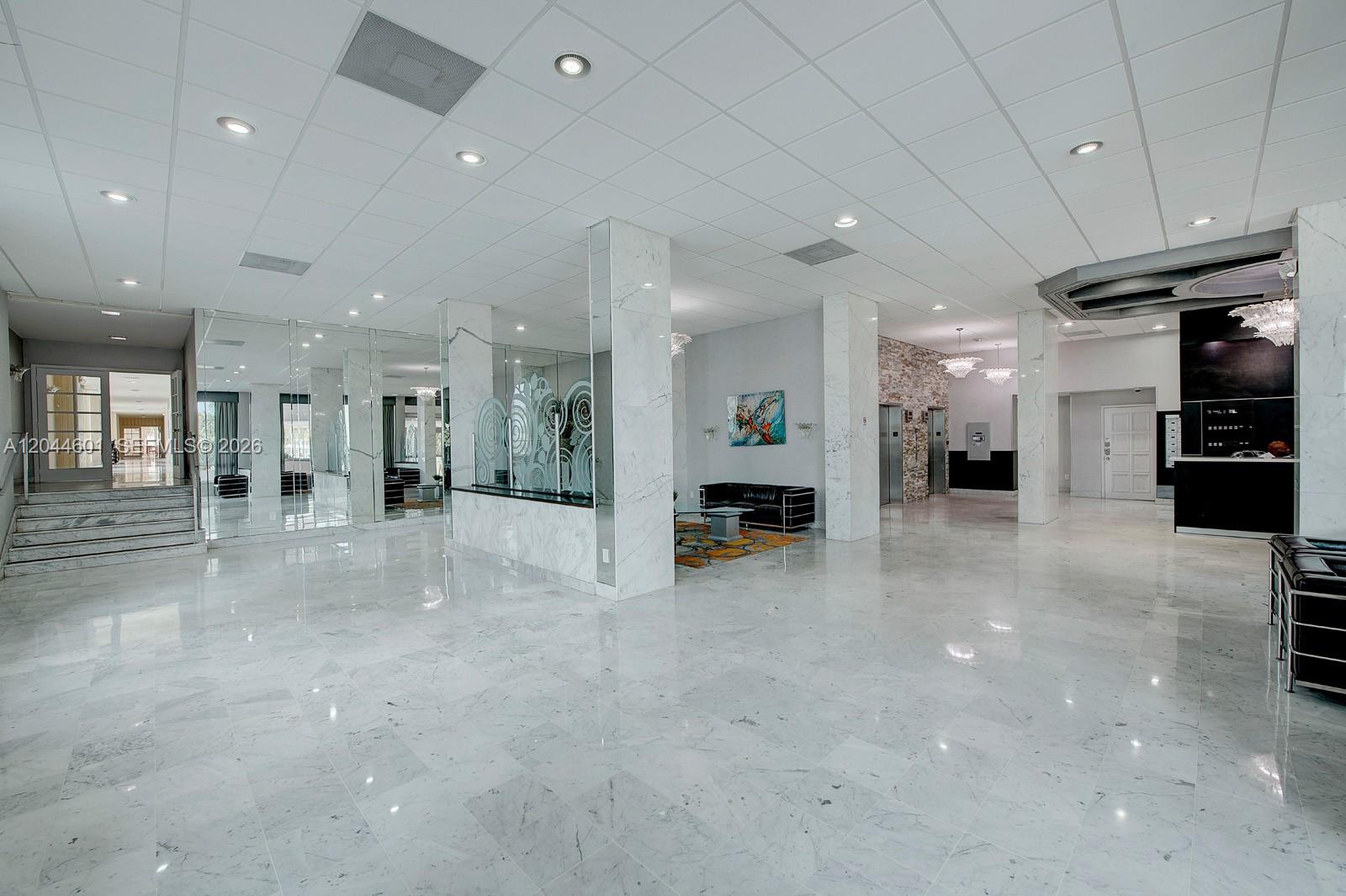 A spacious lobby features white marble flooring, mirrored walls, and several seating areas — 5001 Collins Ave # 9H, Miami Beach FL 33140, MIAMI BEACH, FL