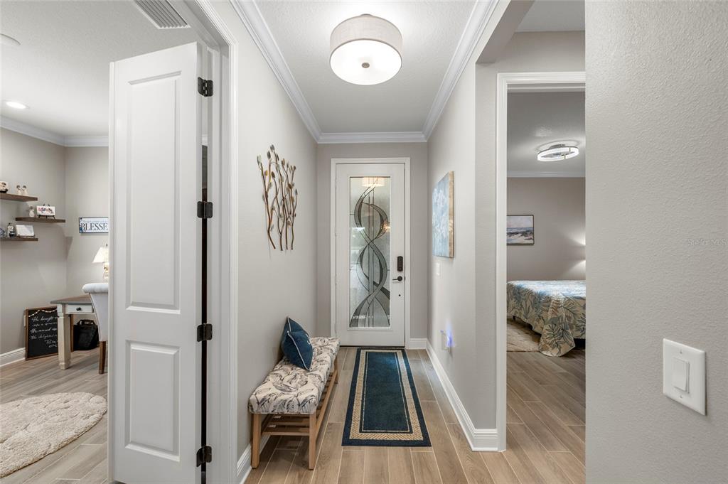 A bright entryway features a patterned bench, a decorative front door, and light wood flooring — 10169 LAKE WALES CIRCLE, SARASOTA, FL