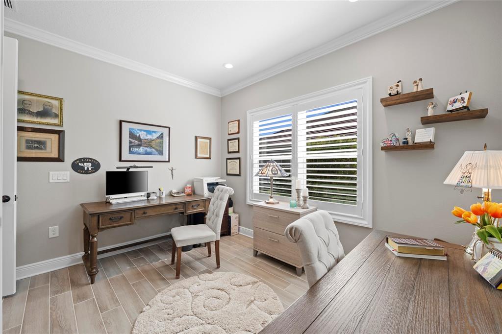 A home office features two wooden desks, upholstered chairs, a round rug, and plantation shutters — 10169 LAKE WALES CIRCLE, SARASOTA, FL