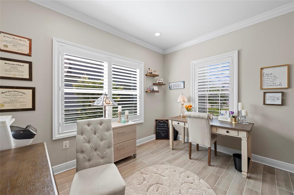 A home office features two desks, tufted chairs, plantation shutters, and framed diplomas on the wall — 10169 LAKE WALES CIRCLE, SARASOTA, FL