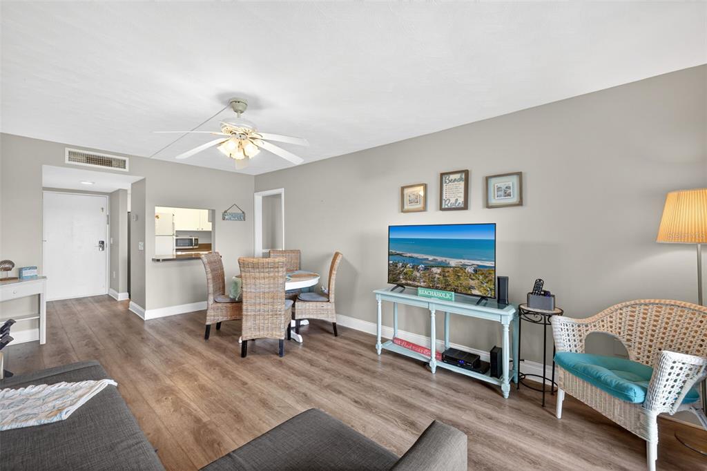 A living room with wood-look flooring, a dining set, and a television on a console — 19451 GULF BOULEVARD UNIT 204, INDIAN SHORES, FL