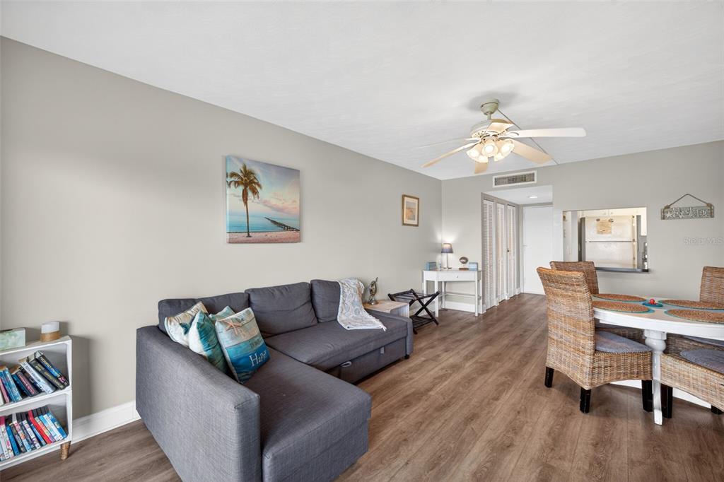A living and dining area features a gray sectional sofa, wood-look flooring, and wicker chairs — 19451 GULF BOULEVARD UNIT 204, INDIAN SHORES, FL
