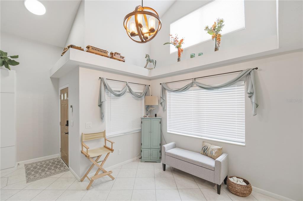 A bright entryway features a vaulted ceiling, tile flooring, a chandelier, and two windows — 56 LAKE FOREST PLACE, PALM COAST, FL