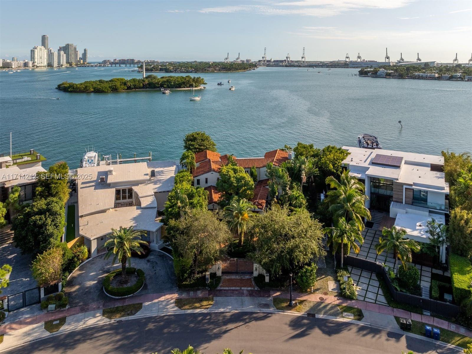 An aerial view shows three waterfront homes with lush landscaping along a curved street — 11 E Rivo Alto Dr, Miami Beach FL 33139, MIAMI BEACH, FL