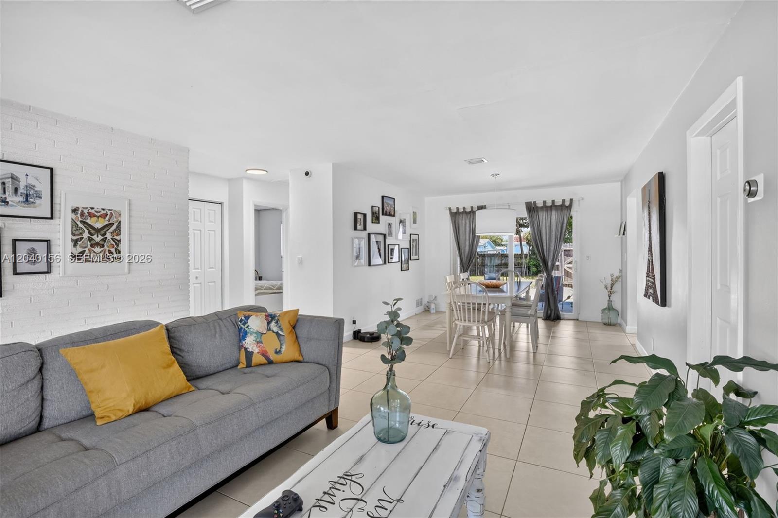 A living room with a gray sofa, white brick wall, and an adjacent dining area — 2220 N 40th Ave, Hollywood FL 33021, HOLLYWOOD, FL
