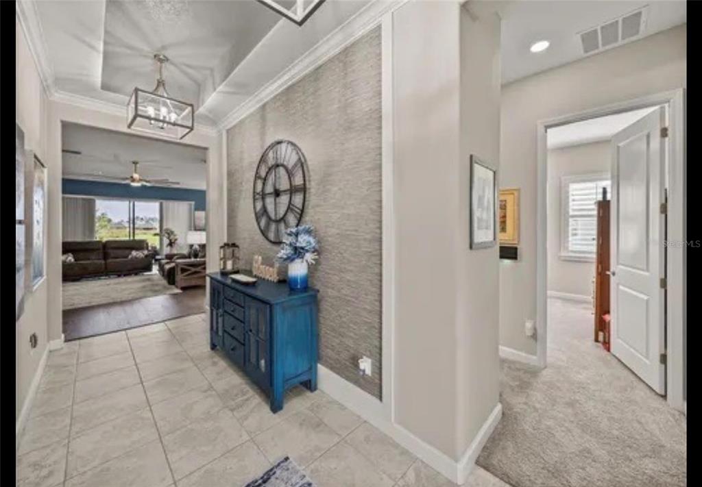 A tiled entryway features a blue console table against a textured wall with a large clock — 31475 CABANA RYE AVENUE, SAN ANTONIO, FL