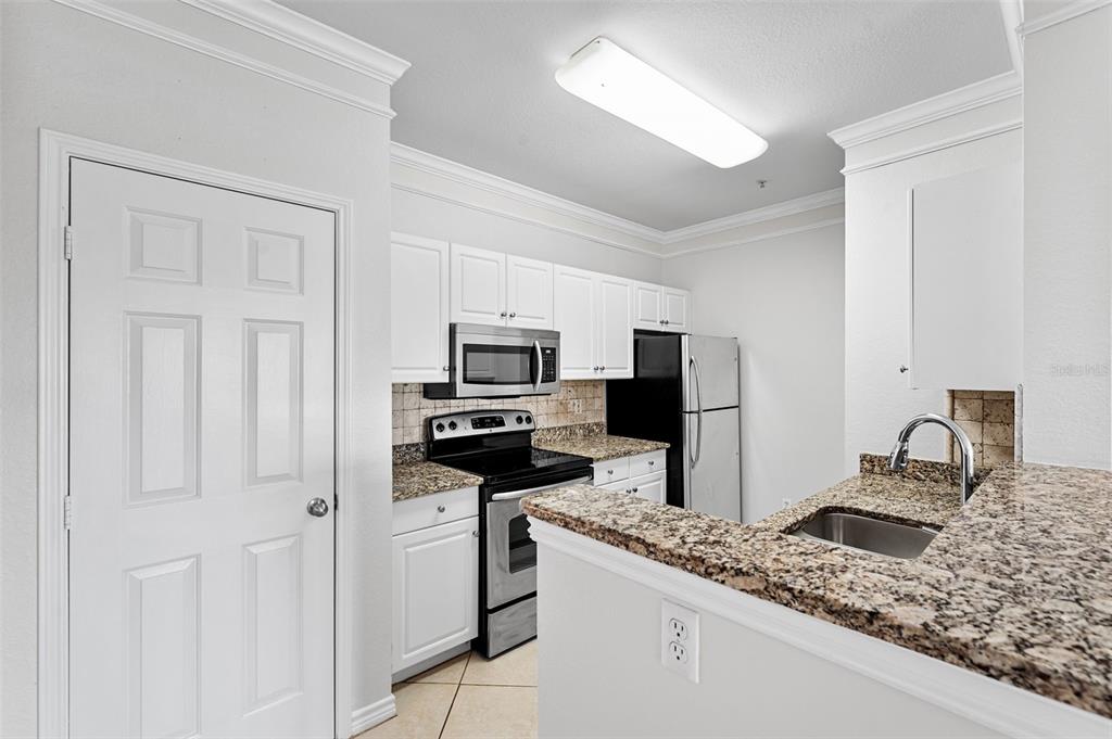 A kitchen features white cabinets, granite countertops, stainless steel appliances, and a breakfast bar — 4305 BAYSIDE VILLAGE DRIVE UNIT 202, TAMPA, FL
