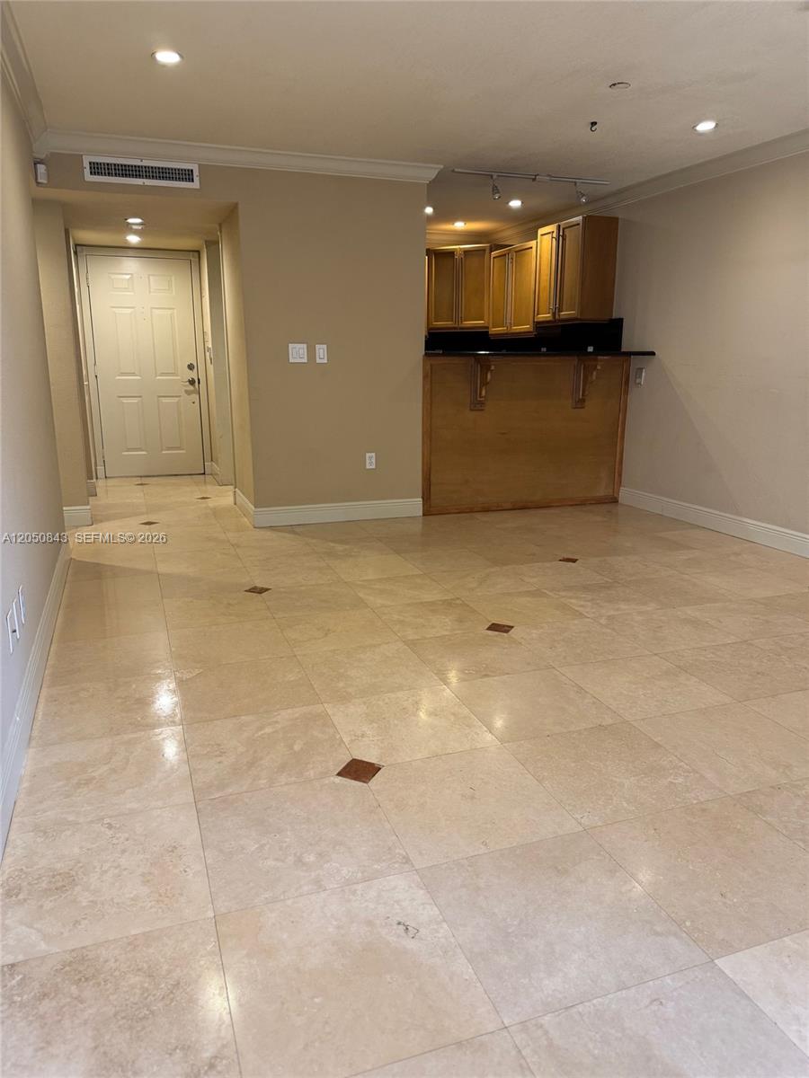 A room with beige tile flooring features a kitchen area with wooden cabinets and counters — 9301 SW 92nd Ave # 212B, Miami FL 33176, MIAMI, FL