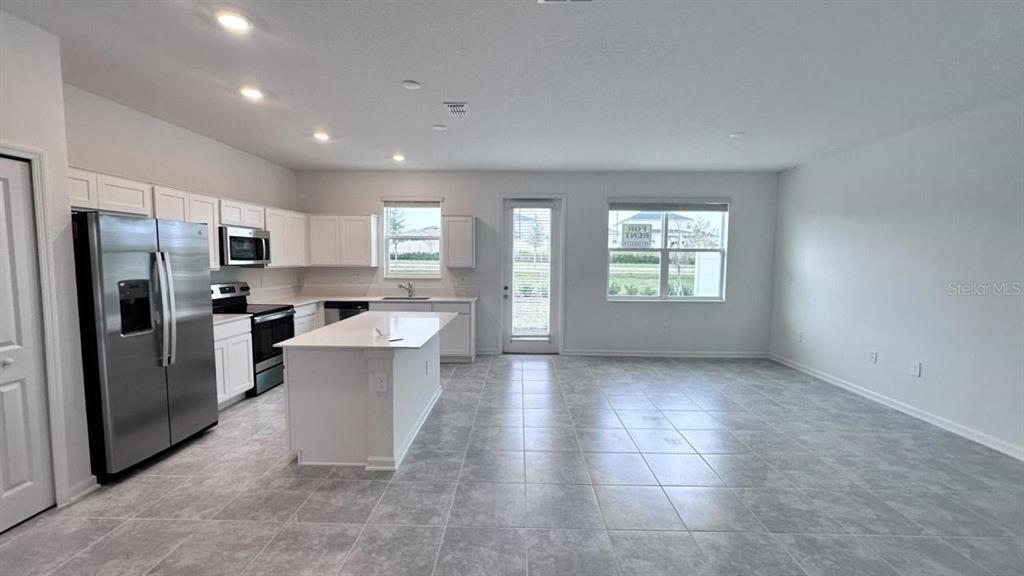 A kitchen with white cabinets, stainless steel appliances, and a central island on tiled floors — 334 BOGEY DRIVE, DAVENPORT, FL