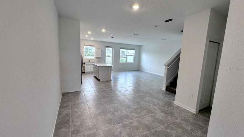 An open-concept kitchen and living area features tile flooring, white cabinetry, and a staircase — 334 BOGEY DRIVE, DAVENPORT, FL