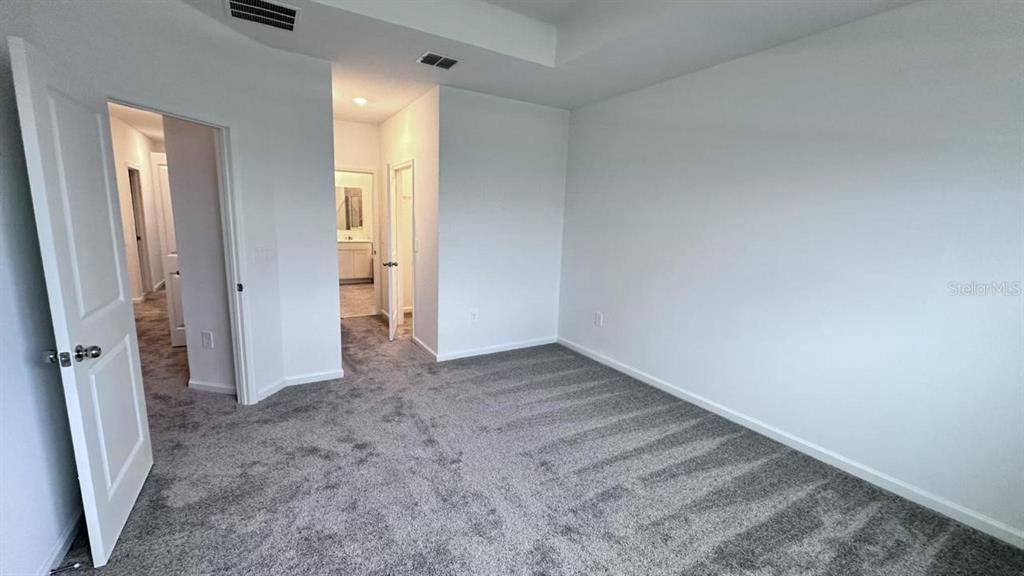 An empty bedroom features gray carpet, white walls, and two open doorways leading to other rooms — 334 BOGEY DRIVE, DAVENPORT, FL