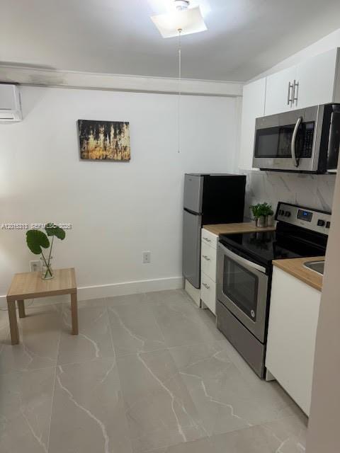 A small kitchen features stainless steel appliances, white cabinets, and light gray tiled flooring — 1270 NE 210th Ter # B, Miami FL 33179, MIAMI, FL