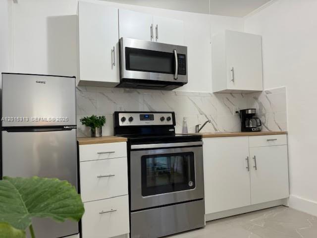 A kitchen features white cabinets, stainless steel appliances, and a marble-patterned backsplash — 1270 NE 210th Ter # B, Miami FL 33179, MIAMI, FL