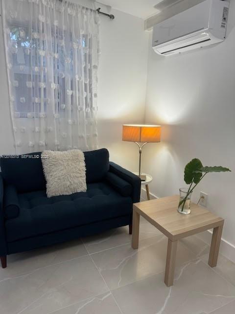 A small room features a dark blue loveseat, a side table with a lamp, and an air conditioner — 1270 NE 210th Ter # B, Miami FL 33179, MIAMI, FL