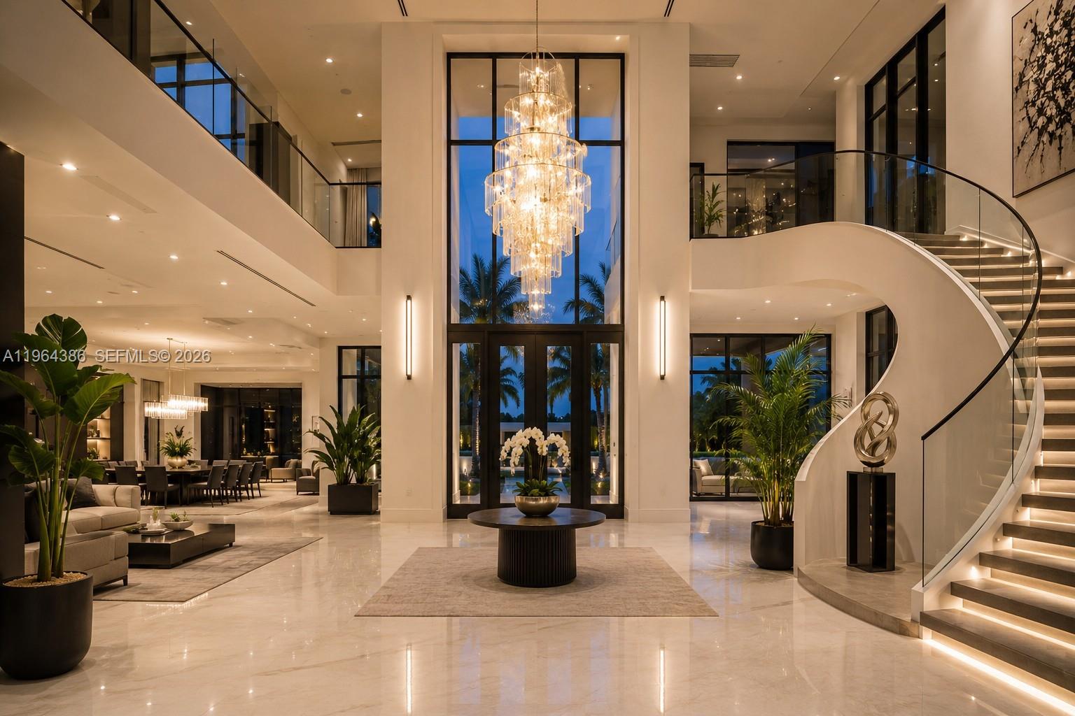 A grand foyer features a double-height ceiling, a large crystal chandelier, and a curved staircase — 14799 SW 48th Ct, Miramar FL 33027, MIRAMAR, FL