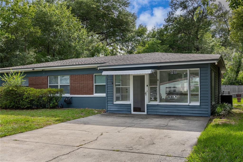 A single-story house with blue siding, a brick section, and a concrete driveway — 1318 NE 14TH STREET, GAINESVILLE, FL