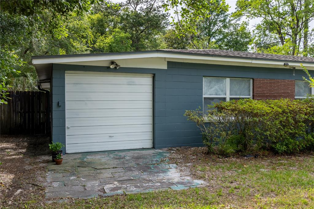 The exterior of a house features a white garage door, gray block walls, and brick accents — 1318 NE 14TH STREET, GAINESVILLE, FL