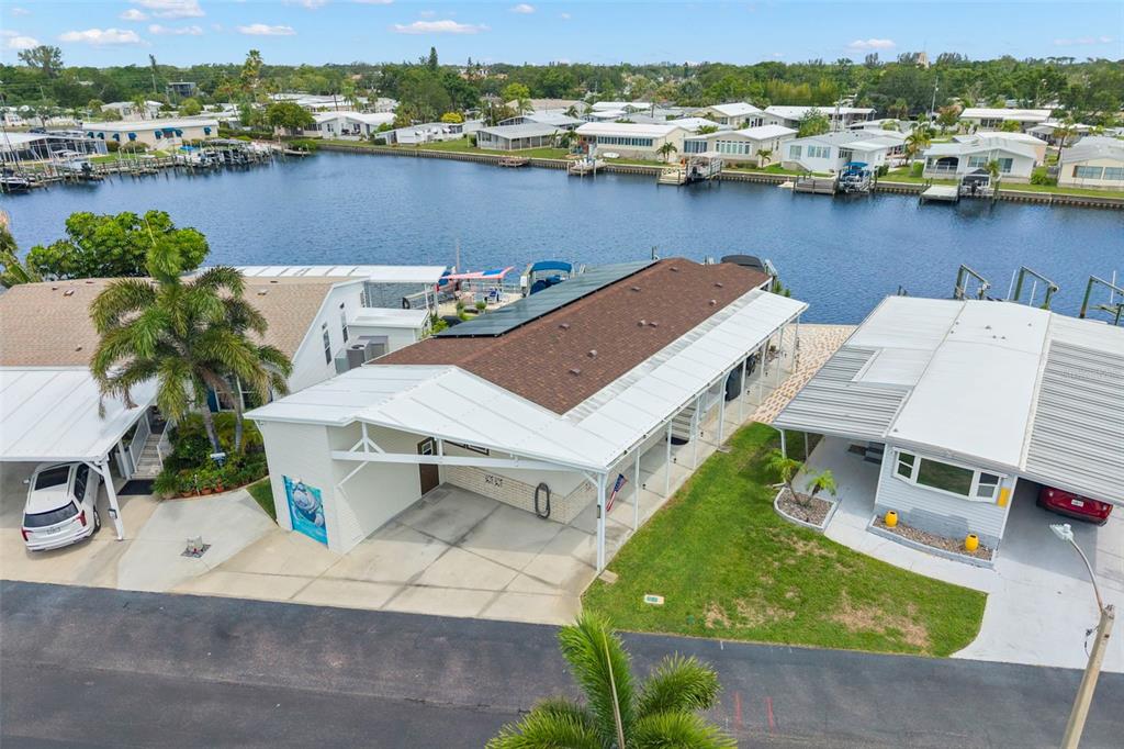 An aerial view shows a waterfront mobile home with a carport and solar panels — 7174 MOUNT ARLINGTON DRIVE NE UNIT 419, ST PETERSBURG, FL
