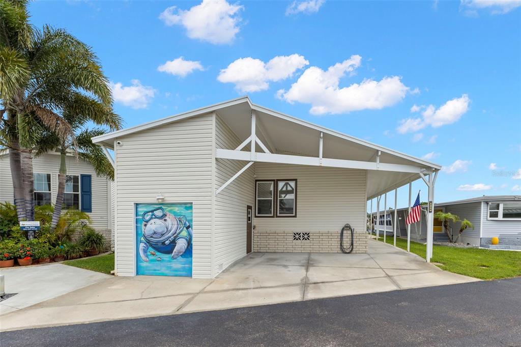 A light-colored mobile home features a carport, a manatee mural, and a palm tree — 7174 MOUNT ARLINGTON DRIVE NE UNIT 419, ST PETERSBURG, FL