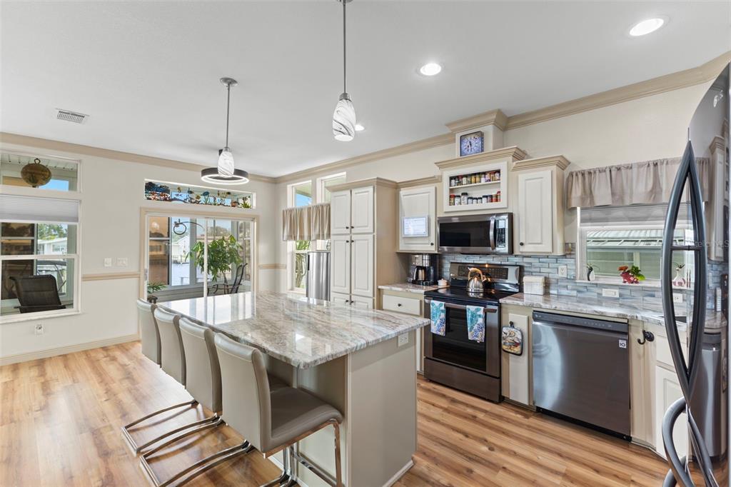 A kitchen features a granite-topped island, stainless steel appliances, and light-colored cabinetry — 7174 MOUNT ARLINGTON DRIVE NE UNIT 419, ST PETERSBURG, FL