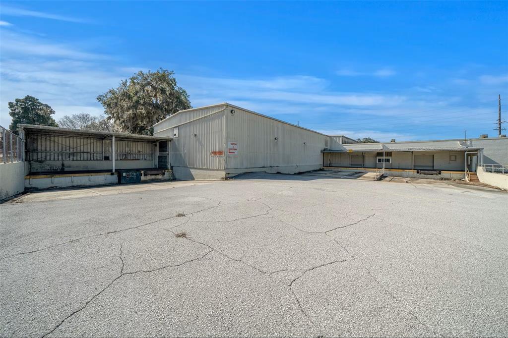 An exterior view of a metal industrial warehouse building with loading docks and cracked asphalt — 506 SE 3RD AVENUE, OCALA, FL