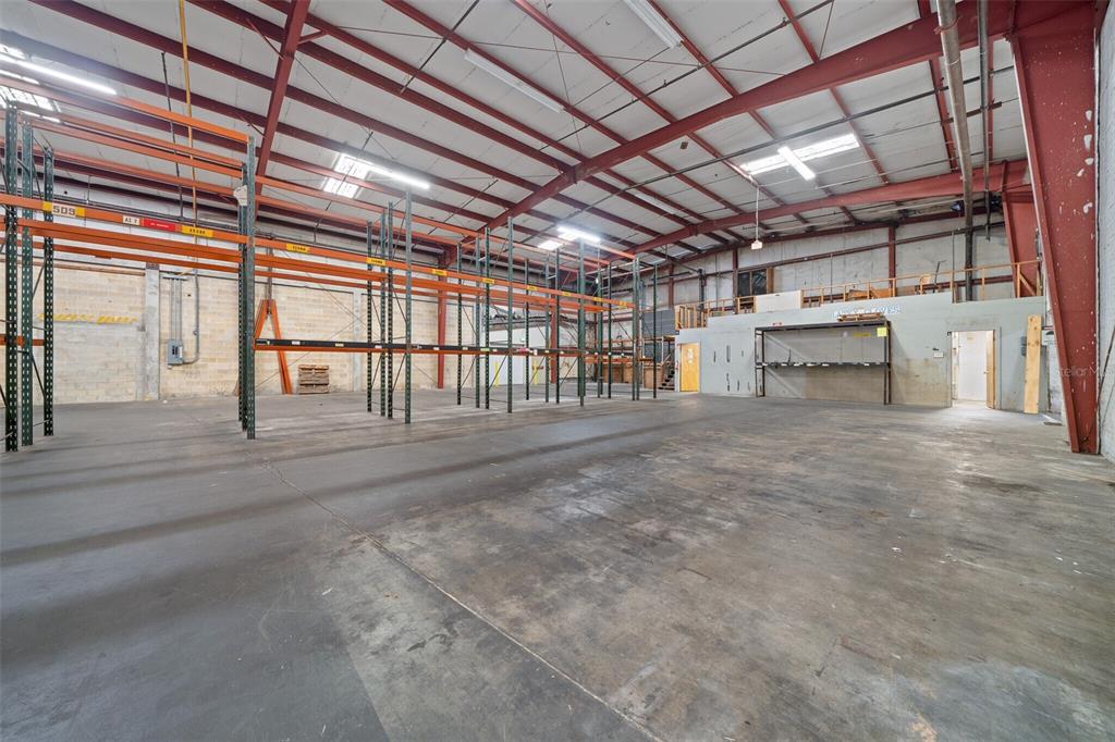 An expansive warehouse interior features high ceilings, exposed steel beams, and industrial pallet racking — 506 SE 3RD AVENUE, OCALA, FL