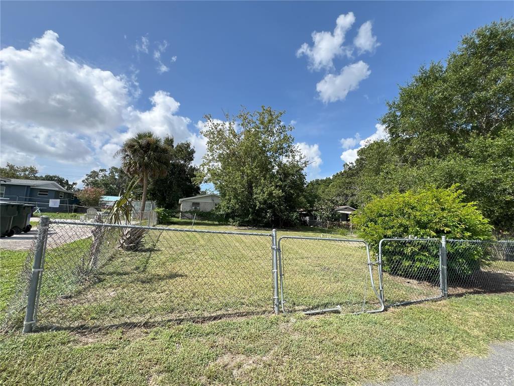 A chain-link fence encloses a grassy vacant lot with trees and a palm tree — 510 PICKENS STREET, LAKELAND, FL