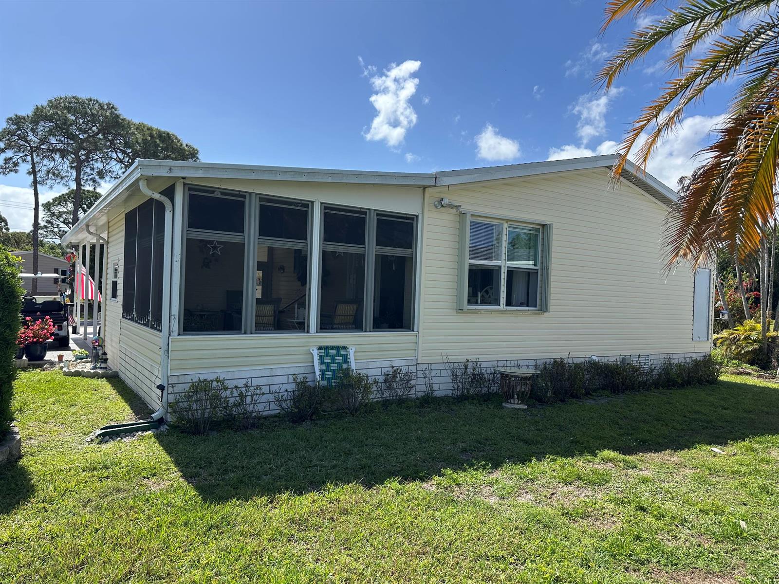 A light yellow mobile home features a screened-in porch and a single window on the side — 500 Thames Bluff Ridge # 24, Fort Pierce FL 34982, FORT PIERCE, FL