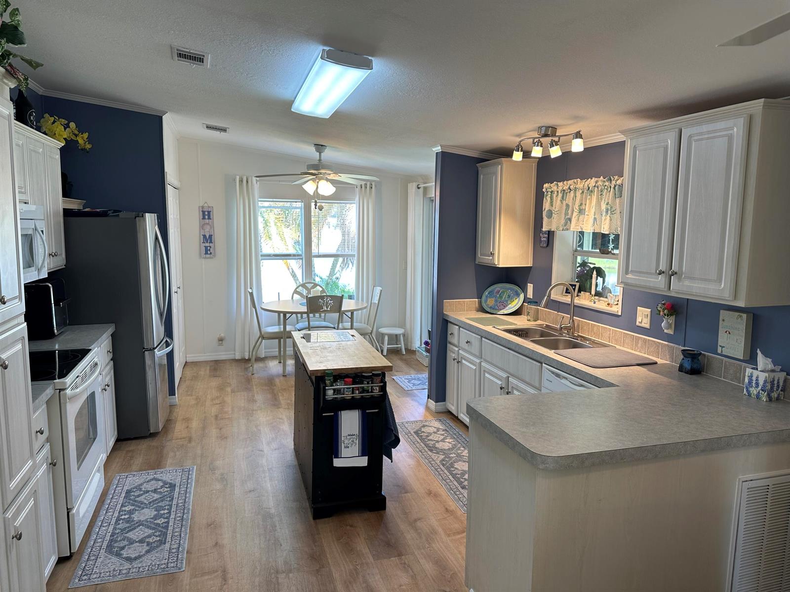 A kitchen with white cabinets, blue walls, a central island, and an adjacent dining area — 500 Thames Bluff Ridge # 24, Fort Pierce FL 34982, FORT PIERCE, FL