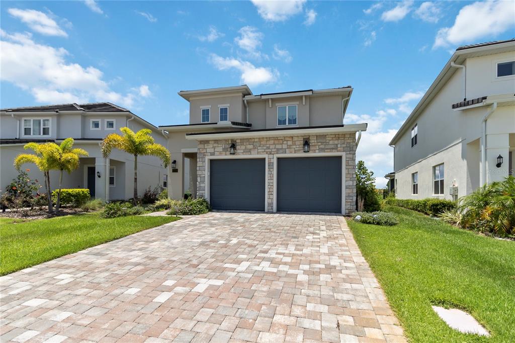 A two-story house with a stone facade, two-car garage, and a paved driveway — 15742 VETTA DRIVE, MONTVERDE, FL