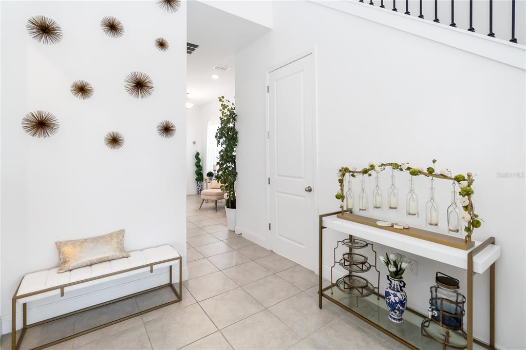 A bright entryway features a white bench, a console table with decor, and wall art — 15742 VETTA DRIVE, MONTVERDE, FL