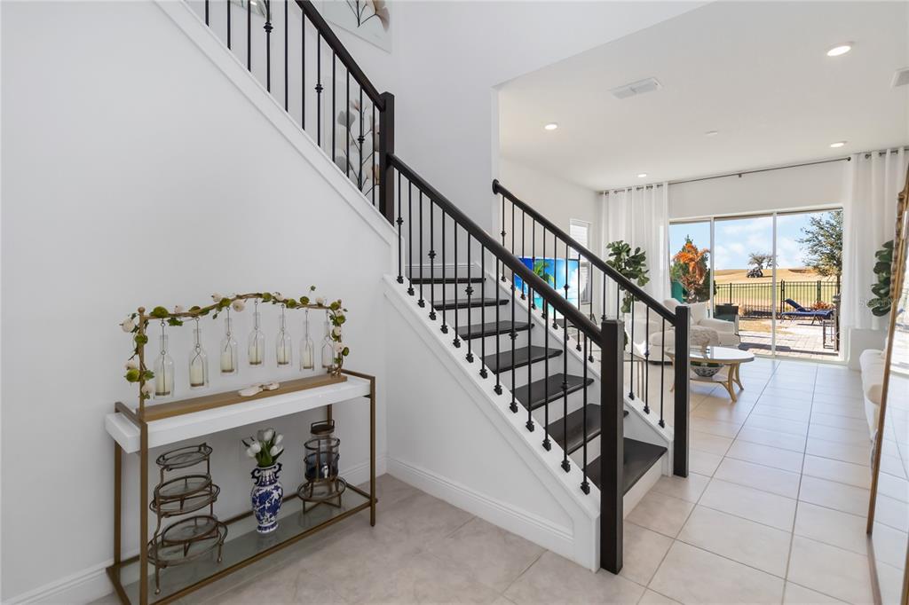An entryway features a staircase with dark wood treads and a metal railing near a console — 15742 VETTA DRIVE, MONTVERDE, FL
