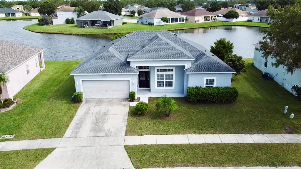 An aerial view of a light blue single-story house with a two-car garage and pond — 3807 WOOD THRUSH DRIVE, KISSIMMEE, FL
