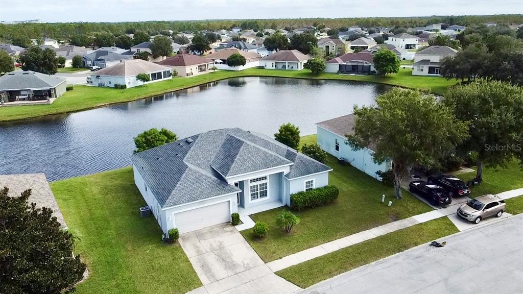 An aerial view of a single-story house with a gray roof beside a pond — 3807 WOOD THRUSH DRIVE, KISSIMMEE, FL