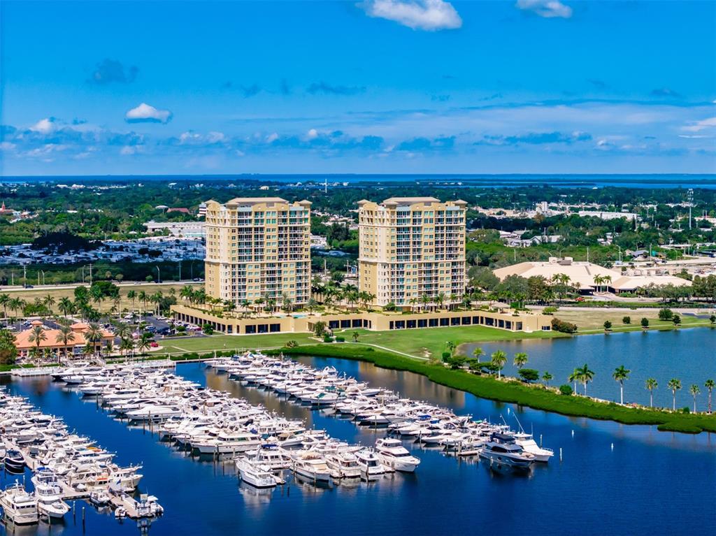 An aerial view shows two high-rise apartment buildings overlooking a large marina filled with boats — 130 RIVIERA DUNES WAY UNIT 802, PALMETTO, FL