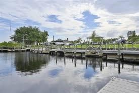 A wooden dock extends into a calm canal with a gazebo and trees in the background — CHANNING AVENUE, NORTH PORT, FL