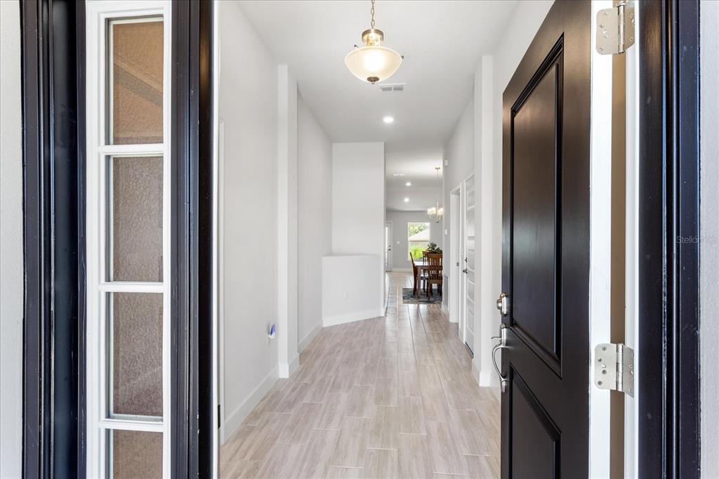 A view from an open front door into a hallway with light-colored tile flooring — 13243 OGDEN GLADE ROAD, DADE CITY, FL