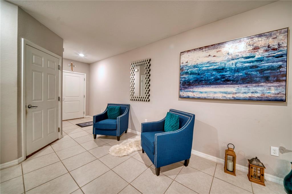 A tiled entryway features two blue armchairs, a mirror, and a large abstract painting — 3390 BELLEZZA COURT, KISSIMMEE, FL