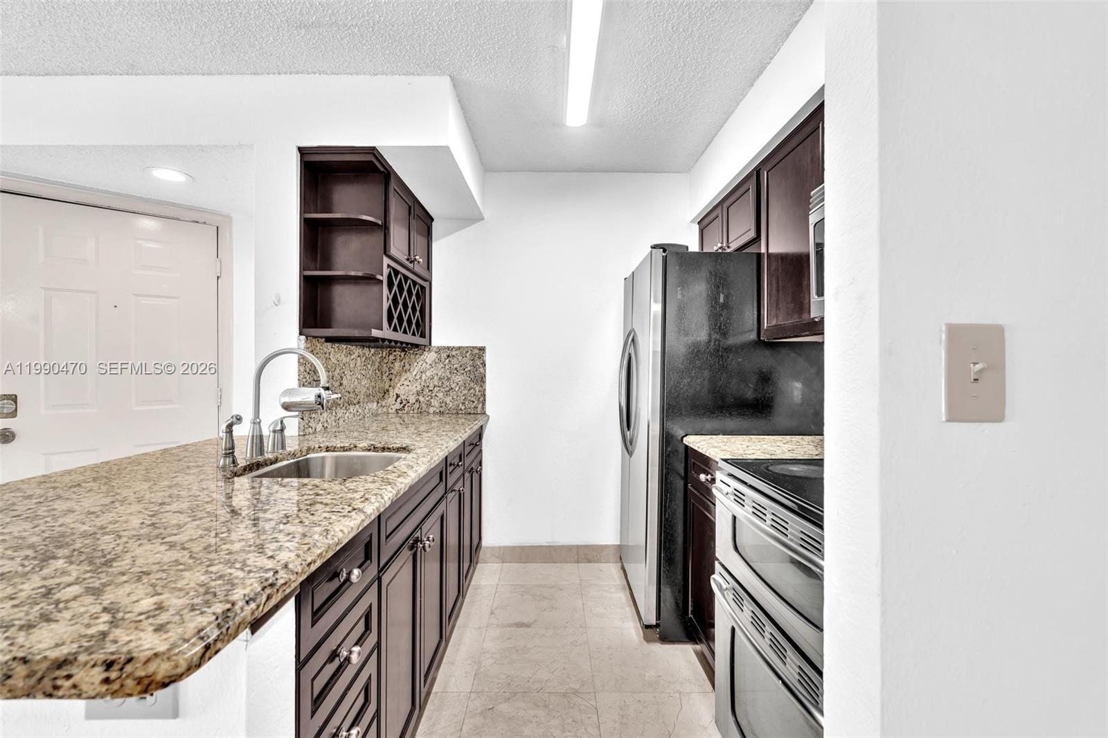 A kitchen features dark wood cabinets, granite countertops, stainless steel appliances, and tile flooring — 2796 S University Dr # 2104, Davie FL 33328, DAVIE, FL