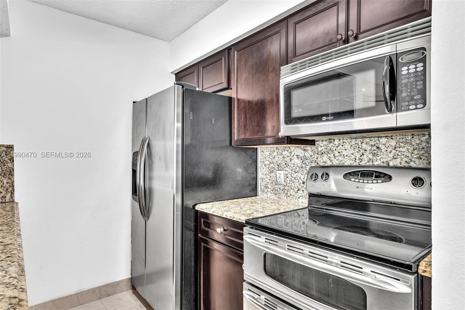 A kitchen features dark wood cabinets, stainless steel appliances, and granite countertops — 2796 S University Dr # 2104, Davie FL 33328, DAVIE, FL