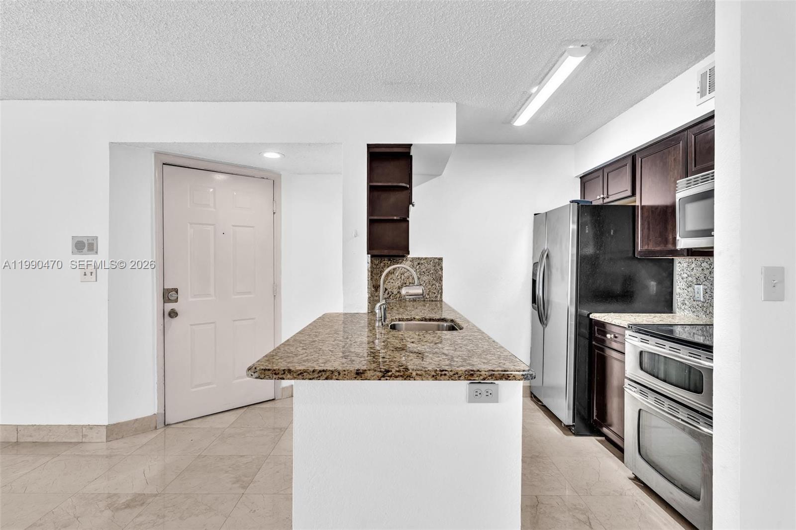 A kitchen features granite countertops, dark wood cabinets, stainless steel appliances, and tile flooring — 2796 S University Dr # 2104, Davie FL 33328, DAVIE, FL