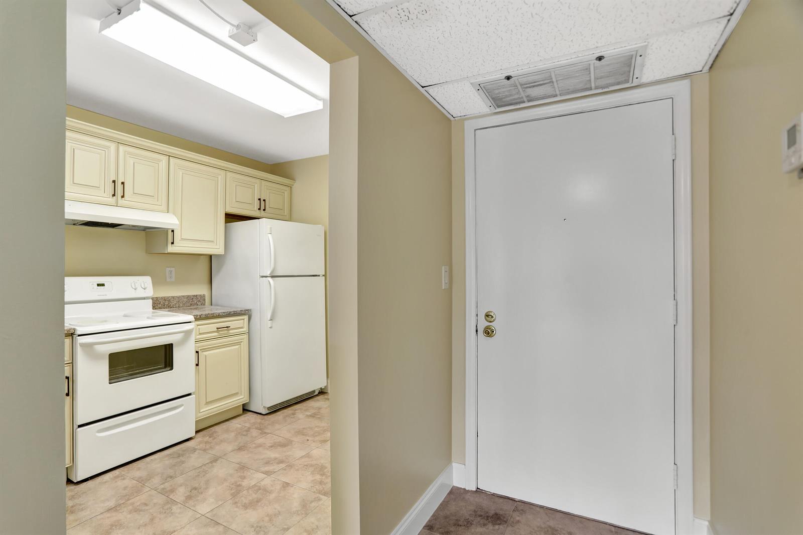 A kitchen with white appliances and cream cabinets is visible through an opening near a door — 3 Royal Palm Way Unit 403, Boca Raton FL 33432, BOCA RATON, FL
